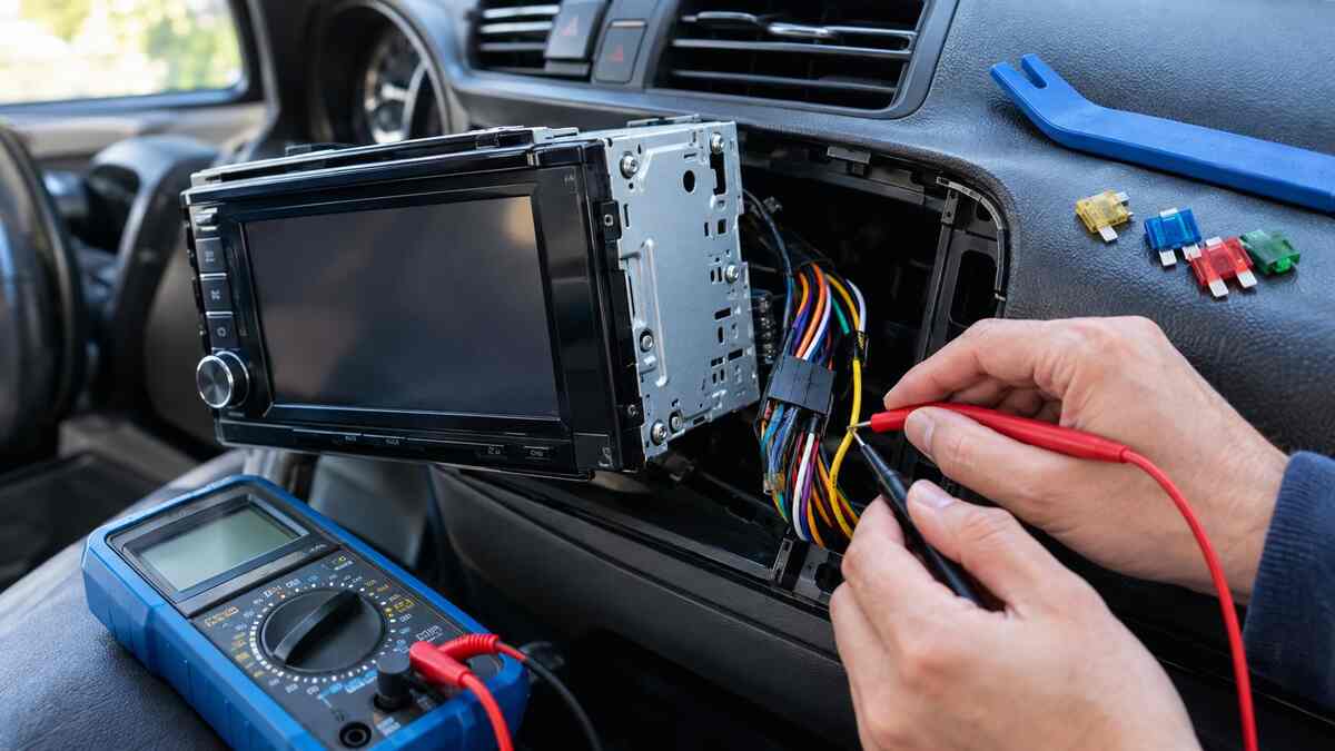 Testing a car stereo wiring harness with a multimeter during Clarion radio repairs